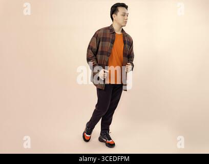 casual young man walking in style on beige background Stock Photo