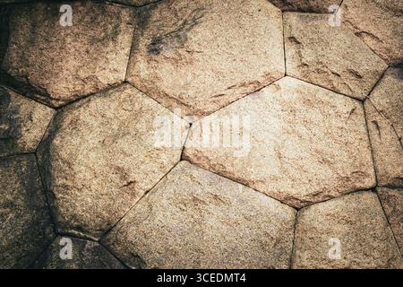 Detailed stone surface featuring a hexagonal arrangement, displaying earthy tones and textures formed over time, perfect for backgrounds or natural de Stock Photo