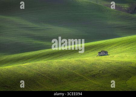 Lone old rural cottage among the rolling hills, landscape in Volterra countryside in spring. Province of Pisa, Tuscany, region, Italy, Europe Stock Photo