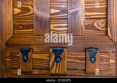 A wooden cabinet with three drawers and a black handle. The cabinet is made of wood and has a rustic look Stock Photo