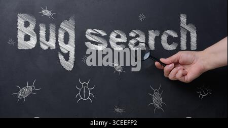 The process of finding and fixing bugs in software code. A person's hand holds a magnifying glass, using which to examine an inscription. Stock Photo