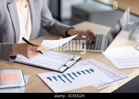 Professional analyzing financial paperwork and charts at work, highlighting data analysis and productivity. Stock Photo