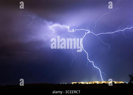 A massive lightning bolt splits the night sky above an apartment complex in Tucson, Arizona, capturing the raw power of desert monsoon storms. Stock Photo