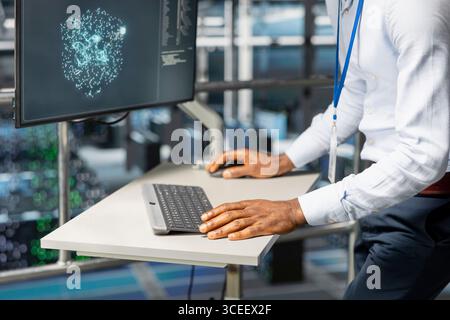 Close up of black engineer overseeing AI code for data automation on pc, reviewing LLM visualization and configuration on industrial platform. Neural network intelligent systems. Stock Photo