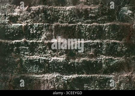 the textured surface of an aged brick wall of an underground tunnel or bridge structure with a distinct beam of sunlight illuminating a portion of its Stock Photo