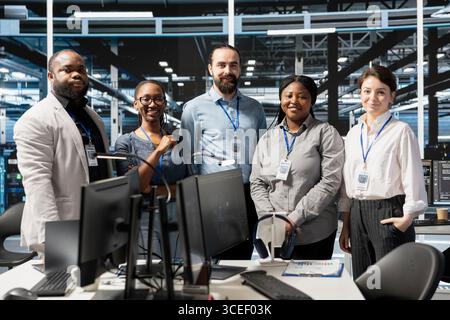 Portrait of cheerful engineering team in data center managing server virtualization, running scripts. Jolly coworkers using programming language in server farm, finetuning network protocols Stock Photo