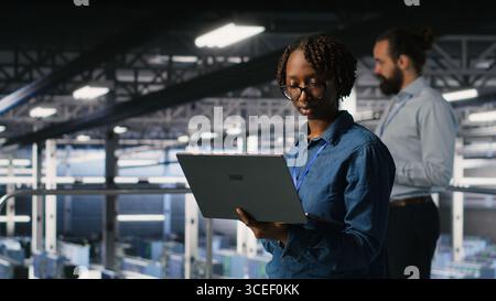 Data center software developers using devices to review AI LLM visualizations. IT professionals working together to analyze neural networks outputs, ensuring stable gear operations Stock Photo