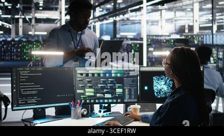 Server farm manager supervising engineer using node tree systems to categorize unstructured data. Data center supervisor overseeing IT expert using natural language processing software, camera A Stock Photo
