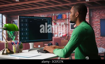Black male freelancer at home uses AI chatbot for task completion, automation and machine learning. Young adult uses artificial intelligence to generate new ideas with prompts. Camera B. Stock Photo