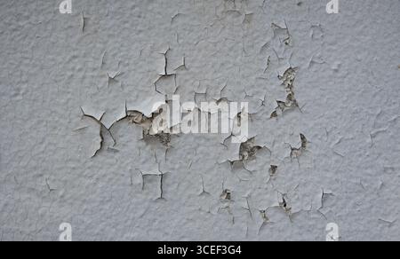 background texture of peeling paint on a cement or plaster wall white paint peeling off to reveal the layer underneath old weathered in need of repair Stock Photo