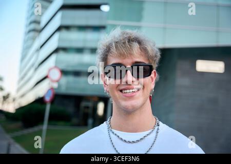 Blond gen z influencer smiling wearing sunglasses and silver chains Stock Photo