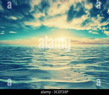 Chill sunset or sunrise seascape with textured waves, below a cloudy sky lit by cool blue tones, creating a tranquil mood Stock Photo