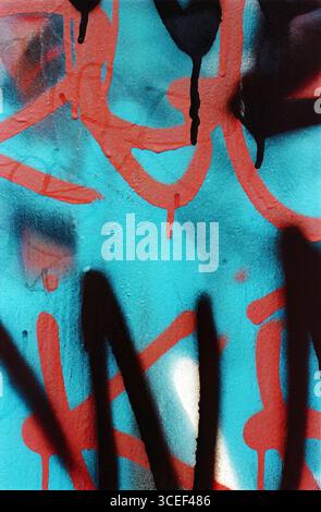 Graffiti art detail with red and black spray paint on a blue textured wall, including abstract patterns and drips Stock Photo
