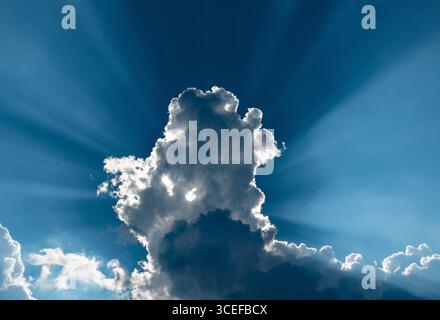 Dramatic sky with deep blue sky, backlit clouds and sunbeams. Stock Photo