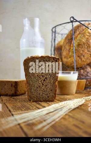 Rustic artisan bread and milk series with loaves, slices, and baskets on wooden tables. Cozy farmhouse food photography showcasing organic bakery, nat Stock Photo