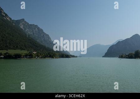 Scenic summer view of Lake Idro in Lombardy, Italy, with green water and surrounding forested mountains under a clear blue sky. Stock Photo