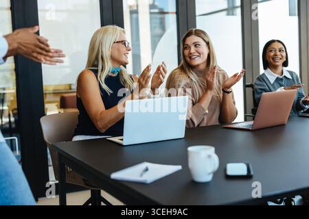 A group of diverse professionals engaging cheerfully around a table in a modern office setting Stock Photo