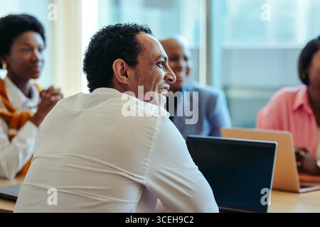 A diverse group of professionals is actively participating in a business meeting. The atmosphere is positive and collaborative, reflecting teamwork an Stock Photo