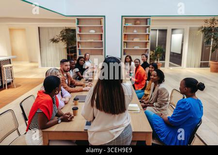 Diverse group of professionals from an advertising agency sit around a conference table for a team briefing. They are engaged in a collaborative discu Stock Photo
