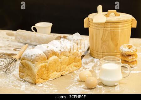 Photo of bread, eggs, milk, donuts and fresh milk on wooden table. Breakfast preparation, daily product. Stock Photo