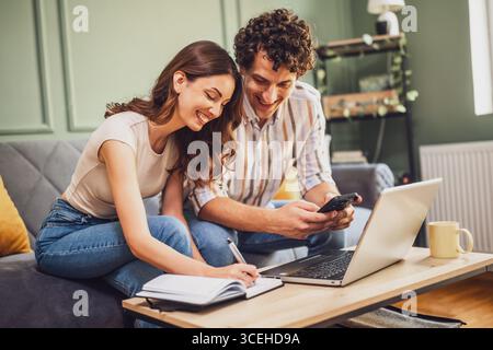 Couple discussing home finance on laptop and calculating family budget in living room. Stock Photo