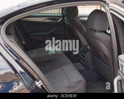 Interior view of modern car's back seats from an open door perspective. The image highlights a spacious passenger area, comfortable upholstery with su Stock Photo