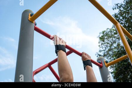 Man doing pull ups workout on the steel bar using a wrist grip. Close up view. Stock Photo