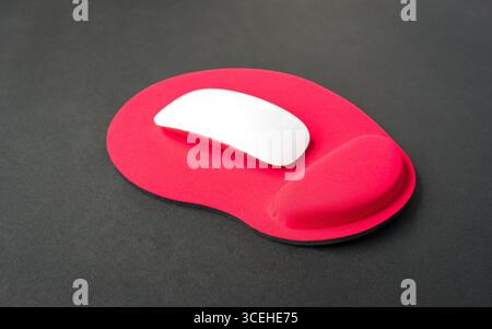 Red color wrist rest mousepad with computer mouse on top. Stock Photo