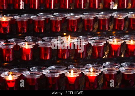 Lots of prayer candles in glass candlesticks. Stock Photo