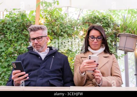 Couple using smartphones at café Stock Photo