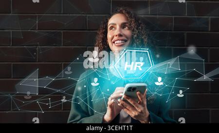 HR professional engaging with technology while smiling outdoors during daytime Stock Photo