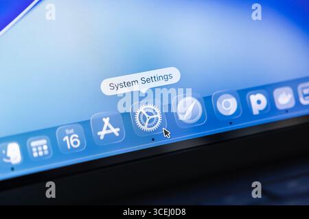 Poznan, Poland - August 15, 2025: Close-up view of macOS 26 desktop, featuring translucent Liquid Glass application icons and a pointer over System Se Stock Photo