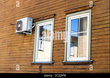Air conditioner unit mounted on wall of old wooden house with aged timber surface Stock Photo
