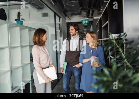 Group of coworkers standing in office corridor and talking. Stock Photo