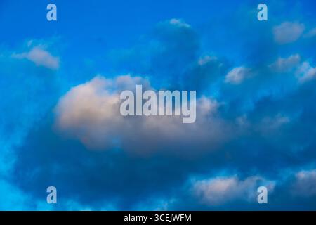 Single fluffy cloud glowing with soft light against a vivid blue sky Stock Photo