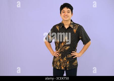 young man with batik outfit, hands on hips with casual pose Stock Photo