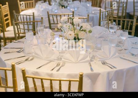 A beautifully arranged dining table showcases white linens, glassware, and a floral centerpiece ready for guests. Stock Photo