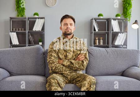 Man wearing military camouflage, arms being crossed, serious, soldier suffers with war memories Stock Photo