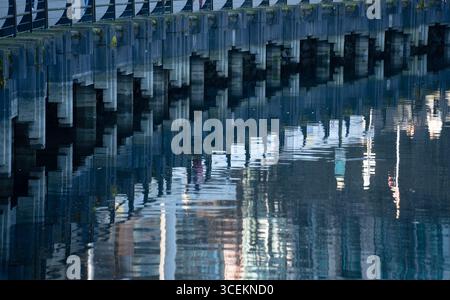 reflection in the water in pier at Vancouver waterfront rectangular shapes of concrete posts reflecting in water horizontal image of pattern in water Stock Photo