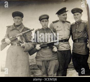 Hungary 1944 WWII. Four Soviet Army officers in uniform stand together. Two of them hold weapons. One of the men wears a hat. Stock Photo