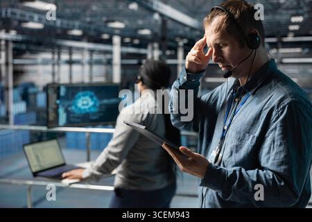 Server hub technicians identifying hardware issues using predictive machine learning alerts, guiding users. Teamworking data center coworkers using headset mic, using AI to resolve clients issues Stock Photo