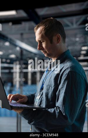Data center engineer analyzing system performance, reducing downtime and preventing equipment failures. Server farm employee automating anomaly detection during routine operations Stock Photo