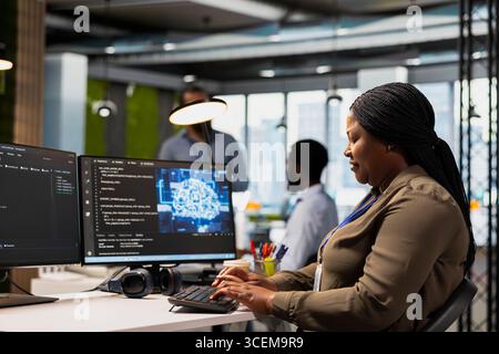 System administrator in office using AI automation scripts to reduce repetitive coding tasks. Woman using artificial intelligence technology on PC in high tech startup workspace Stock Photo
