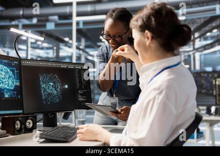 Cheerful data center admins doing fist bump, celebrating successful AI implementation. Jolly server hub teamworking coworkers excited after optimal results achieved by artificial intelligence model Stock Photo