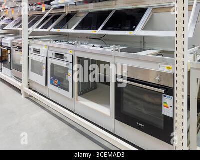 Riga, Latvia - August 13, 2025: Modern kitchen appliances displayed in a retail store, featuring various ovens and cooktops, showcasing sleek designs Stock Photo