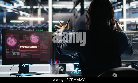 Panicked engineer in AI server facility reacts to hacking incident involving theft of sensitive data. Data center employee alarmed by computer virus triggered by security systems, camera B Stock Photo