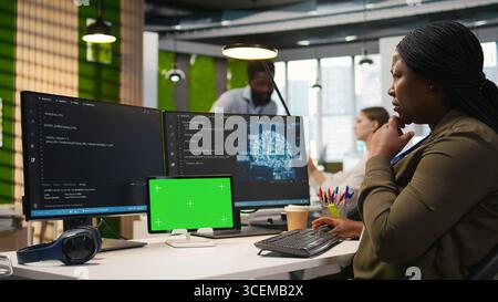 Admin using isolated screen tablet to code AI algorithms debugging software issues and improving system stability. Tech startup office worker using chroma key device, configuring settings, camera A Stock Photo