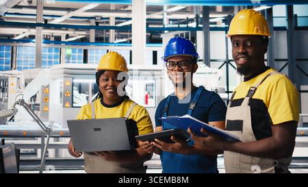 Solar panels engineers team developing new photovoltaic materials using devices in the manufacturing plant. Black workers group conducting experiments for better production line. Camera B. Stock Photo