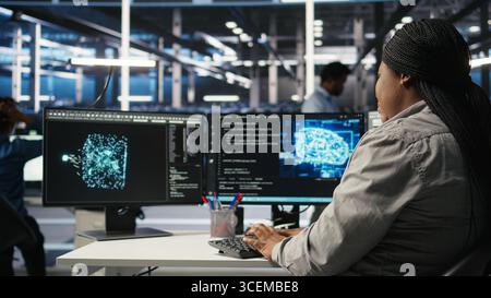Data center employee deploying AI solutions optimizing equipment. Server farm software developer applying artificial intelligence technology minimizing infrastructure downtime, camera A Stock Photo