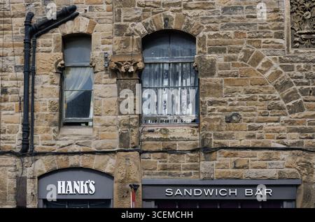 A modern sandwich bar below old carvings on a stone wall Edinburgh building, Scotland Stock Photo